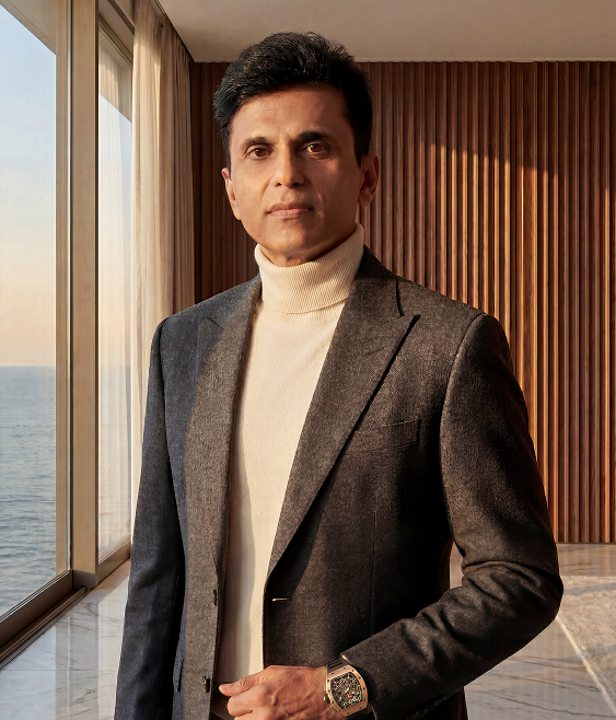 Mr. Anand Pandit at a drawing table, marking up a floor plan, elevations pinned on the wall behind him.